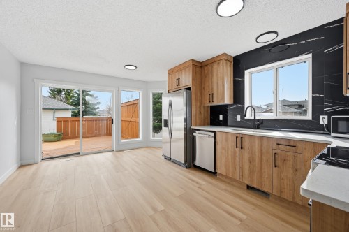 Kitchen and dining area featuring wood-finish flooring, light wood cabinetry, white countertops, and a black and white veined backsplash - 631 Jenner Cove Cove, Edmonton, AB 