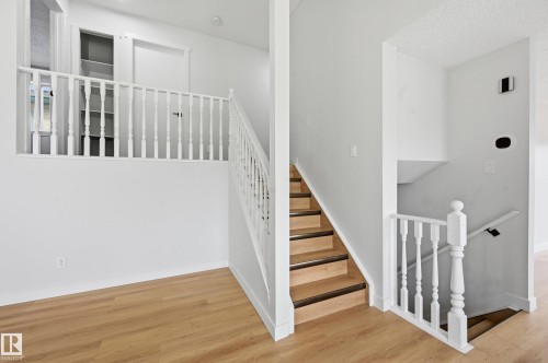 Split-level entry featuring light wood-finish flooring, white painted walls, and a white baluster railing system - 631 Jenner Cove Cove, Edmonton, AB 
