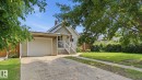 Siding exterior with an attached garage, concrete driveway, and front porch with white railings - 10115 104 Street, Westlock, AB 