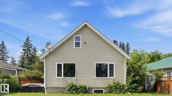 Gabled exterior featuring horizontal siding, white trim, and a prominent front window arrangement - 