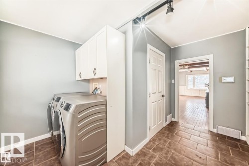 Laundry area featuring overhead cabinetry, track lighting, and rectangular floor tiles - 10115 104 Street, Westlock, AB 