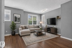 Spacious living area featuring wood-finish flooring, multiple windows with blinds, track lighting, and a neutral color palette - 