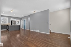 Spacious interior featuring wood-finish flooring, a kitchen island with seating, stainless steel appliances, and recessed lighting - 