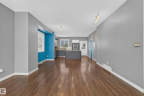 Open-concept living space featuring wood-finish flooring, recessed lighting, track lighting, a kitchen with a central island, and stainless steel appliances - 24 655 Watt Boulevard, Edmonton, AB 