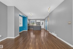 Open-concept living space featuring wood-finish flooring, recessed lighting, track lighting, a kitchen with a central island, and stainless steel appliances - 
