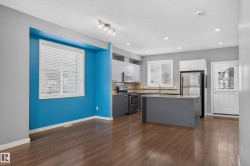 Open-concept living space featuring wood-finish flooring, a modern kitchen island with an integrated sink, stainless steel appliances, and abundant recessed lighting - 