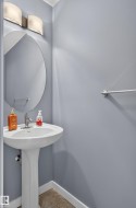 Pedestal sink with chrome faucet, oval mirror, and wall-mounted light fixture - 