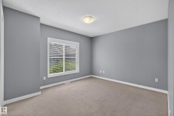 Carpeted room featuring a single window with blinds, ceiling-mounted light fixture, and neutral gray wall paint - 