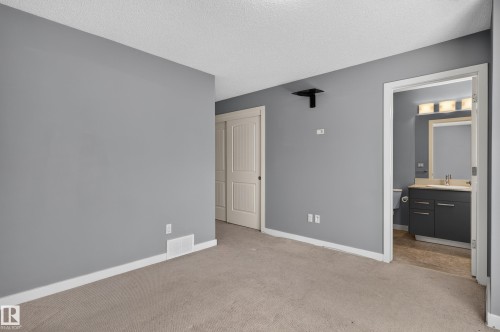 Spacious room with light gray walls, textured ceiling, and neutral-toned carpet - 24 655 Watt Boulevard, Edmonton, AB 