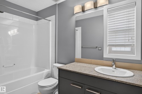 Bathroom featuring a single vanity with an oval sink, a light-toned countertop, and a dark base cabinet - 24 655 Watt Boulevard, Edmonton, AB 