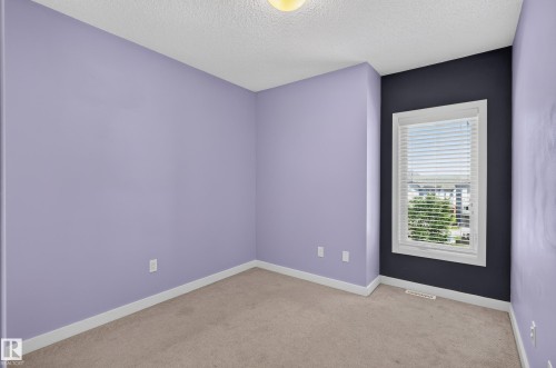 Carpeted room featuring a single window with blinds, white trim, and a textured ceiling - 24 655 Watt Boulevard, Edmonton, AB 