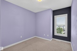 Carpeted room featuring a single window with blinds, white trim, and a textured ceiling - 