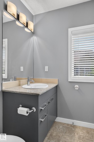 Bathroom vanity featuring a light-toned countertop, an undermount sink, and a chrome faucet - 24 655 Watt Boulevard, Edmonton, AB 