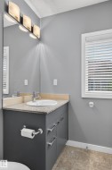 Bathroom vanity featuring a light-toned countertop, an undermount sink, and a chrome faucet - 