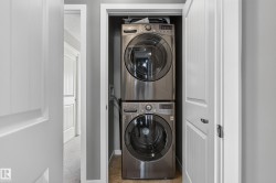 Dedicated laundry closet featuring a stacked washer and dryer, tile flooring, and white paneled doors - 