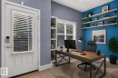 Dedicated workspace featuring a built-in shelving unit, wood-finish desktop, and multiple floating shelves - 24 655 Watt Boulevard, Edmonton, AB 