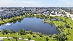 Community featuring a substantial central pond surrounded by green spaces and paved pathways - 