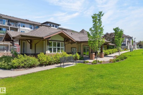 Clubhouse exterior featuring a gabled roofline, wood-finish siding, large windows, and a covered entry - 24 655 Watt Boulevard, Edmonton, AB 