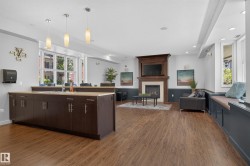 Open-concept room featuring wood-finish flooring and a central island with dark cabinetry and a light-toned countertop - 