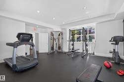 Dedicated fitness area featuring black rubber flooring, recessed lighting, white walls, and a window with exterior views - 