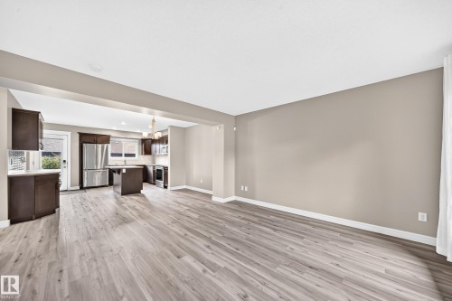 Expansive living area featuring light wood-finish flooring, neutral wall tones, and an open layout to the kitchen - 69 Tonewood Boulevard, Spruce Grove, AB - Indoor