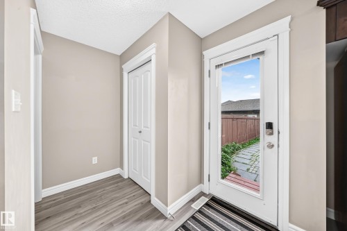 Entryway featuring a full-light exterior door with smart lock, wood-finish flooring, a bi-fold closet, and neutral wall paint - 69 Tonewood Boulevard, Spruce Grove, AB - Indoor Photo Showing Other Room