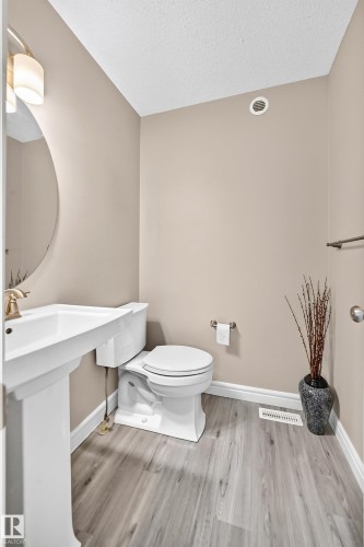 Pedestal sink with brass-finish faucet, toilet, and wood-finish flooring - 69 Tonewood Boulevard, Spruce Grove, AB - Indoor Photo Showing Bathroom