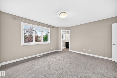 Spacious room featuring neutral tone walls, grey carpet flooring, a large window, and a white interior door - 69 Tonewood Boulevard, Spruce Grove, AB - Indoor Photo Showing Other Room