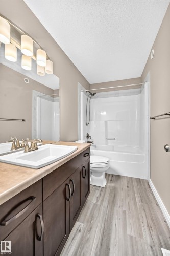 Bathroom featuring a contemporary dark wood-finish vanity with a light countertop, integrated sink, and a modern light fixture - 69 Tonewood Boulevard, Spruce Grove, AB - Indoor Photo Showing Bathroom