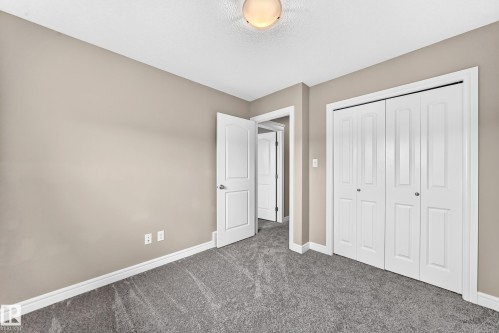 Room featuring neutral-toned walls, grey carpet flooring, white baseboards, a white paneled door, and a white bi-fold closet - 69 Tonewood Boulevard, Spruce Grove, AB - Indoor