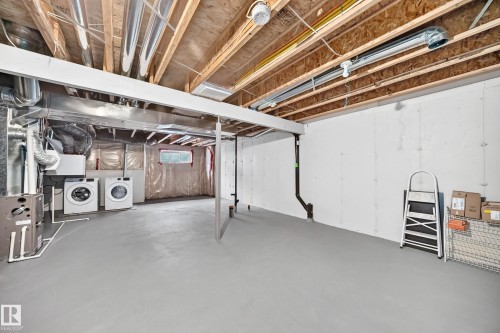 Unfinished basement with exposed ceiling joists and ductwork, featuring a light grey floor, white walls, and dedicated laundry area with appliances - 69 Tonewood Boulevard, Spruce Grove, AB - Indoor Photo Showing Basement
