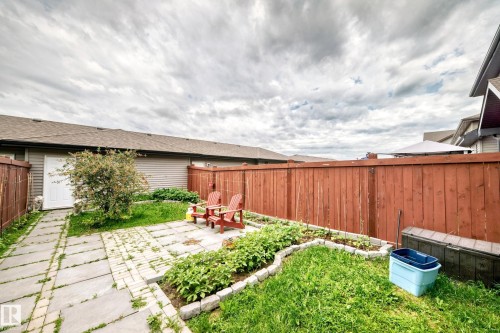 Private rear yard featuring a wood privacy fence, stone paver patio, and garden beds with retaining stone - 69 Tonewood Boulevard, Spruce Grove, AB - Outdoor