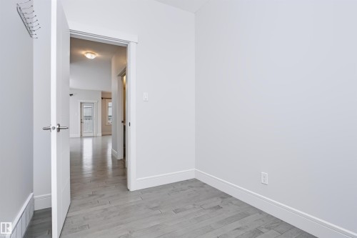 Interior space featuring light gray wood-finish flooring, white baseboards, and a white door with a polished chrome handle - 1235 164 Street, Edmonton, AB 