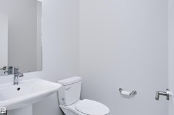 Pedestal sink with chrome faucet, a rectangular mirror, and a white toilet - 