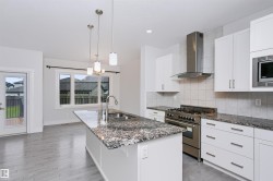 Modern kitchen featuring a large island with an undermount sink and pendant lighting - 