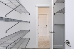 Open closet with wire shelving system, white interior walls, and grey baseboards - 