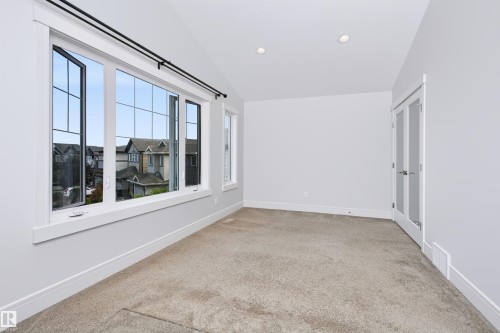 Spacious room featuring multiple large windows with grid patterns, recessed ceiling lighting, textured carpeting, and white trim - 1235 164 Street, Edmonton, AB 