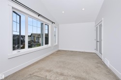 Spacious room featuring multiple large windows with grid patterns, recessed ceiling lighting, textured carpeting, and white trim - 