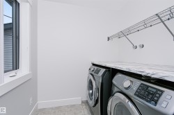 Dedicated laundry area featuring a window, built-in wire shelving, a stone-finish countertop, and tile flooring - 
