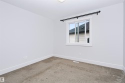 Neutral color palette room featuring a single window with white trim, a black curtain rod, and light-colored carpeting - 
