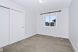 Neutral-toned bedroom featuring plush carpet flooring, white trim, and a window with a black curtain rod - 