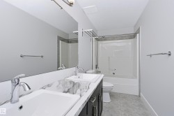 Bathroom featuring a dual vanity with undermount sinks and a marble-patterned countertop, a full-width mirror, a tub/shower combination with tile surround, and tile flooring - 