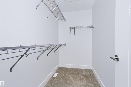 Walk-in closet with carpet flooring, white baseboards, and wire shelving system - 1235 164 Street, Edmonton, AB 