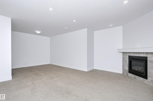 Carpeted room featuring a fireplace with a tiled surround and white mantel - 1235 164 Street, Edmonton, AB 