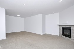 Carpeted room featuring a fireplace with a tiled surround and white mantel - 