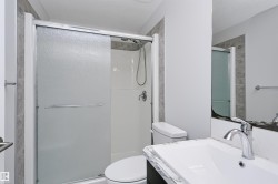 Bathroom with a shower stall featuring sliding frosted glass doors, a white shower surround, and chrome fixtures - 