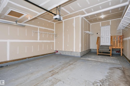 Spacious garage featuring a concrete floor, exposed drywall, and an automatic garage door opener - 1235 164 Street, Edmonton, AB 
