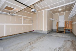 Spacious garage featuring a concrete floor, exposed drywall, and an automatic garage door opener - 