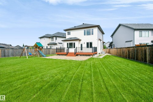Expansive backyard featuring a large green lawn, full privacy fencing, and a multi-level deck with black railings - 1235 164 Street, Edmonton, AB 