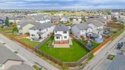 Expansive, fenced backyard featuring a manicured lawn, a multi-level wood-finish deck, and a ground-level patio space - 